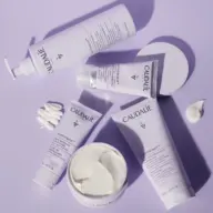 Caudalie skincare products on a purple surface, including creams and lotions.