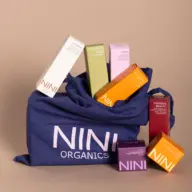 NINI Organics products in a blue bag, including boxes labelled Oat Foam, Detox Foam, and Crimson Beauty.