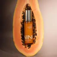 NINI Organics serum bottle inside a halved papaya.