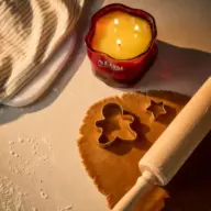 Red candle labelled "NEOM", dough with cutters, rolling pin, and striped cloth.
