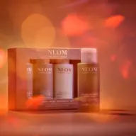 NEOM Body Wash Discovery Set with three bottles against a warm, blurred background.