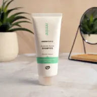 Green People Intensive Repair Shampoo tube on a bathroom counter with plants and a mirror.