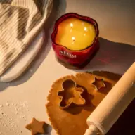 Baking scene with gingerbread dough, rolling pin, star cutter, and lit NEOM candle.