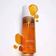 RMS Kakadu Beauty Body Oil, 100 mL bottle with oil droplets on white background.