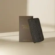 Black konjac sponge with brown packaging on a beige background.