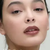 Close-up of a person with natural makeup. Text: "Mallo Coast".