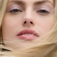 Close-up of a woman's face with pink eyeshadow and lipstick. Text: "Wildflower".