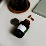 Vitamin C Plus bottle on table with two capsules nearby.