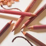Assorted lip pencils with shavings and drawn lines on a light surface.