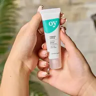 Hands holding a tube of "oy" purifying serum for clear skin.