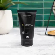 Black tube of Green People Energising Shower Gel on a white surface. Green tiled background.