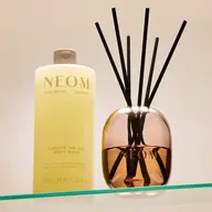 NEOM body wash and diffuser on glass shelf.