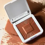 Open compact of rms beauty bronzer with embossed design on scattered powder.