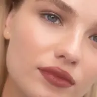 Close-up of a person with smooth skin, red lipstick, and text "NAOMI" in the corner.