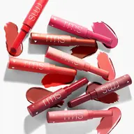 Assorted RMS lipsticks with swatches in various red and pink shades on a white background.