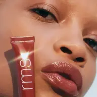 Person with glossy lips holding RMS Liplights tube. Text: "RHAPSODY".