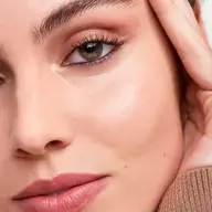 Close-up of a person's face with smooth skin, pink lips, and defined eyebrows.