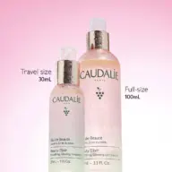 Two Caudalie Beauty Elixir bottles, 30mL and 100mL, on a pink background.
