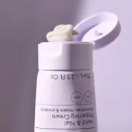 Open tube of hand and nail cream with cream on the lid.