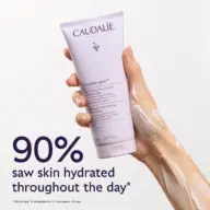 Hand holding Caudalie Vinotherapist body lotion. Text: 90% saw skin hydrated throughout the day.