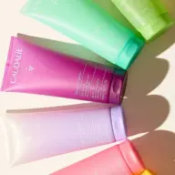 Colourful Caudalie shower gel tubes arranged on a light surface.