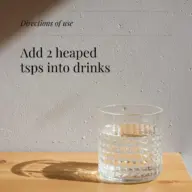 Glass of water on wooden table, text reads: "Add 2 heaped tsps into drinks".