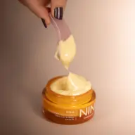 Hand holding spatula with cream above an orange jar labelled "GAIA Face Cream".