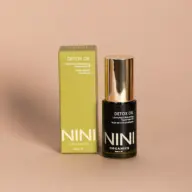 NINI Organics Detox Oil bottle and box on a beige background.