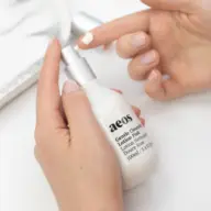 Hands applying aeos Gentle Cleansing Lotion Pink from a white bottle.