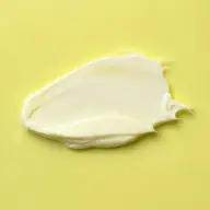 Creamy skincare product on a yellow background.