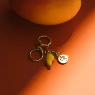 Keyring with mango charm and engraved disc on orange surface.