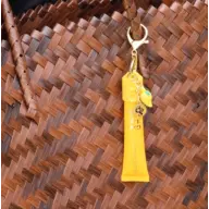 Yellow lip balm tube with keychain on woven brown bag.