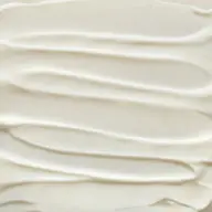 Creamy white skincare product texture with smooth, wavy lines.