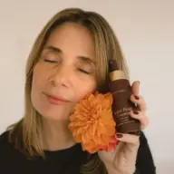 Woman holding Eco by Sonya Super Fruit Hydrator bottle and orange flower.