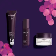 Caudalie Premier Cru skincare set on purple background with pink grape illustrations.