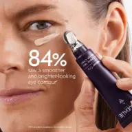 Woman applying eye cream with metal applicator, text: "84% saw smoother, brighter eye contour".