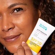 Person holding The Organic Pharmacy SPF 50 sunscreen tube.