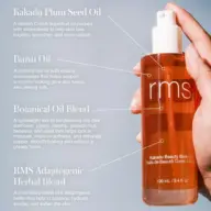 RMS Kakadu Beauty Body Oil bottle held in hand, with text detailing ingredients and benefits.