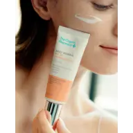 Woman applying The Organic Pharmacy SPF 30 cream to her cheek.
