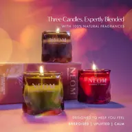 Three lit NEOM candles with packaging, text: "Energised | Uplifted | Calm".