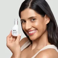 Woman holding aeos Dew Facial Wash bottle, smiling.