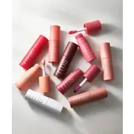 Assorted rms lip gloss tubes with applicators on a white surface.