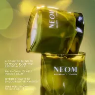 Green NEOM candles with text on essential oils for mood enhancement.