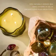 Olive green candle with three wicks, glass baubles, and text about natural wax and UK hand-finishing.