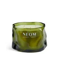 Green glass candle with "NEOM Wellbeing London" text, three wicks visible.
