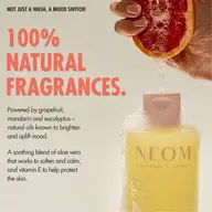 100% natural fragrances text, grapefruit held over NEOM Wellbeing London bottle with bubbles.