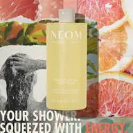 NEOM Squeeze the Day Body Wash with citrus background and text "Your shower. Squeezed with energy.