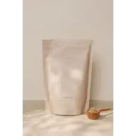 Supernova Living Woman supplement pouch with a wooden scoop of powder on a light surface.