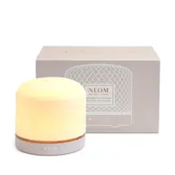 Essential oil diffuser with glowing light, next to Neom branded box.