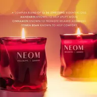 Red NEOM candles with flames, text about essential oils: mandarin, cinnamon, tonka bean.